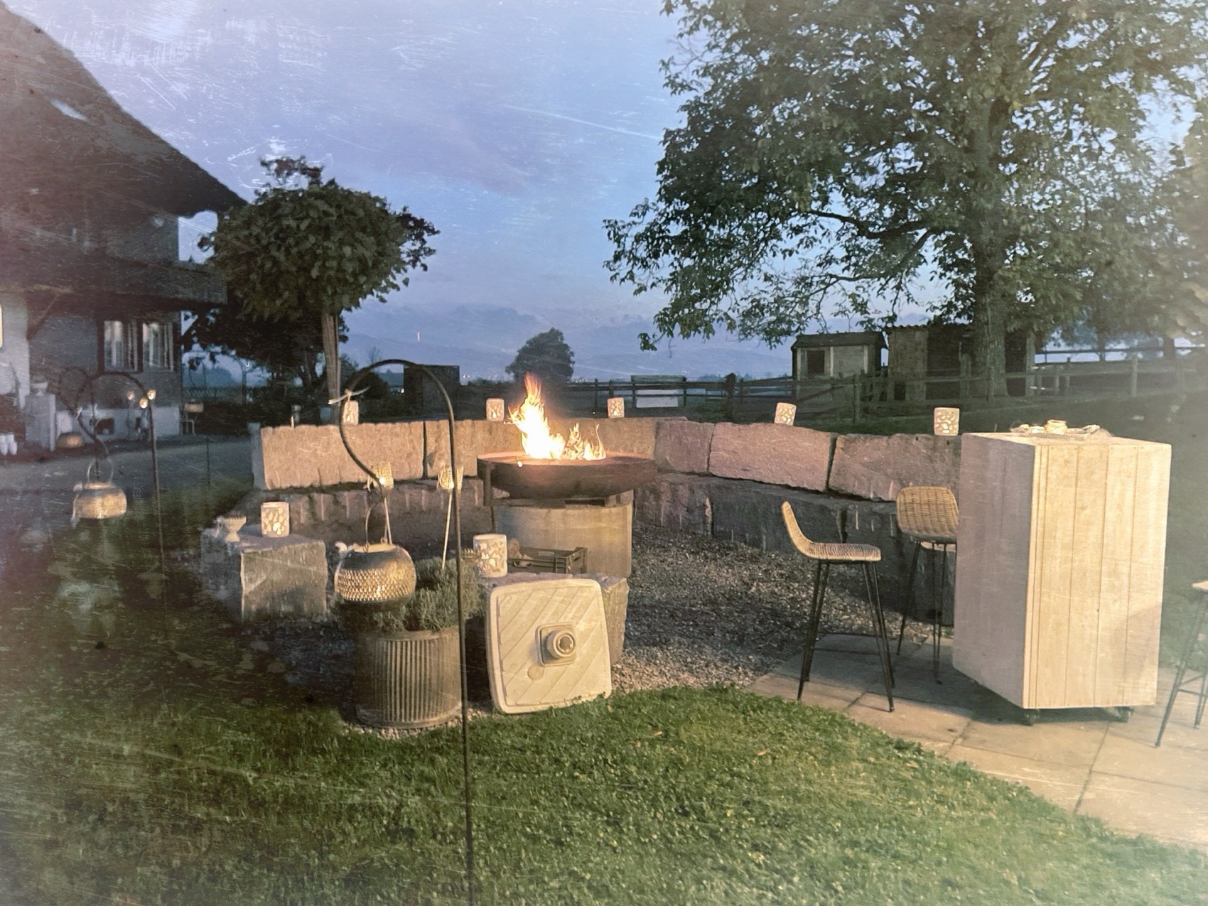 Sitzplatz mit Feuerschale vor dem Hof in der Abenddämmerung