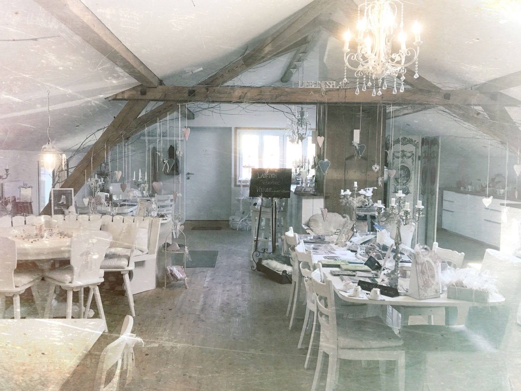Die Bistro-Stube unter den Dachbalken mit Kronleuchter und weiss gedeckten Tischen
