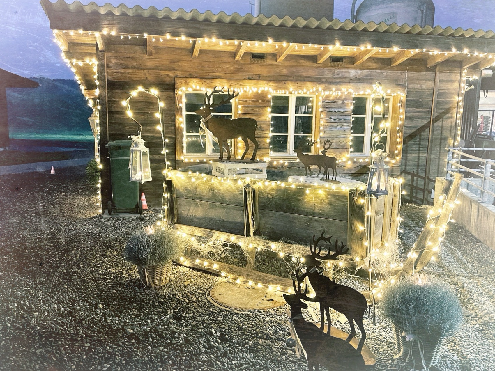 Holzhütte mit Lichterketten vor dem Hof am Abend